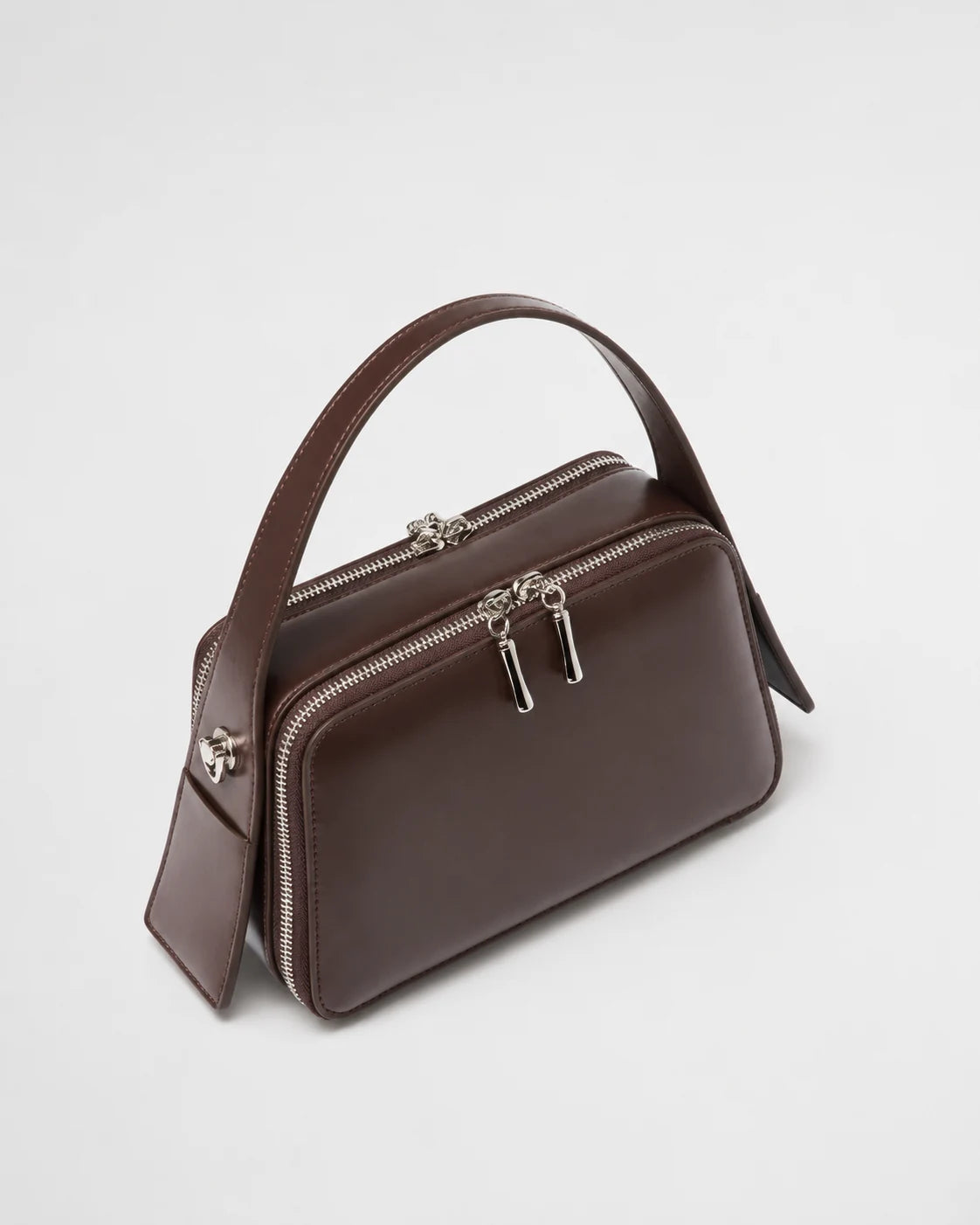 Bolsa feminina de couro marrom Elyra em vista angular, mostrando alça de mão, compartimentos com fechamento em zíper e estrutura compacta.