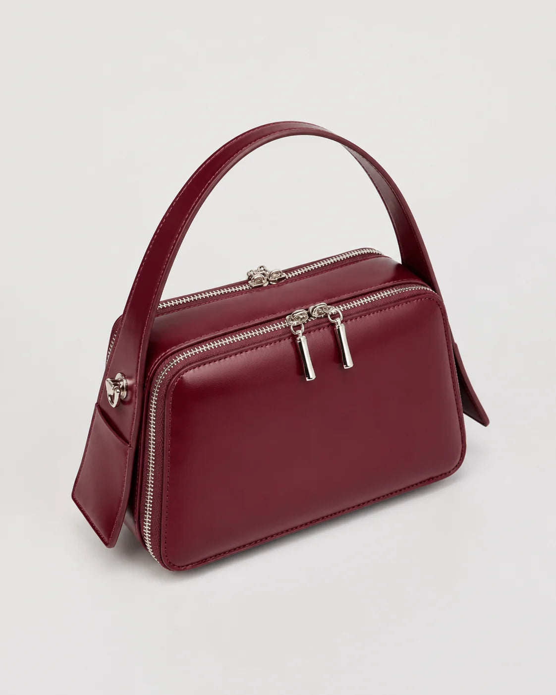Bolsa feminina de couro marsala Elyra em vista angular, mostrando alça de mão, compartimentos com fechamento em zíper e estrutura compacta.