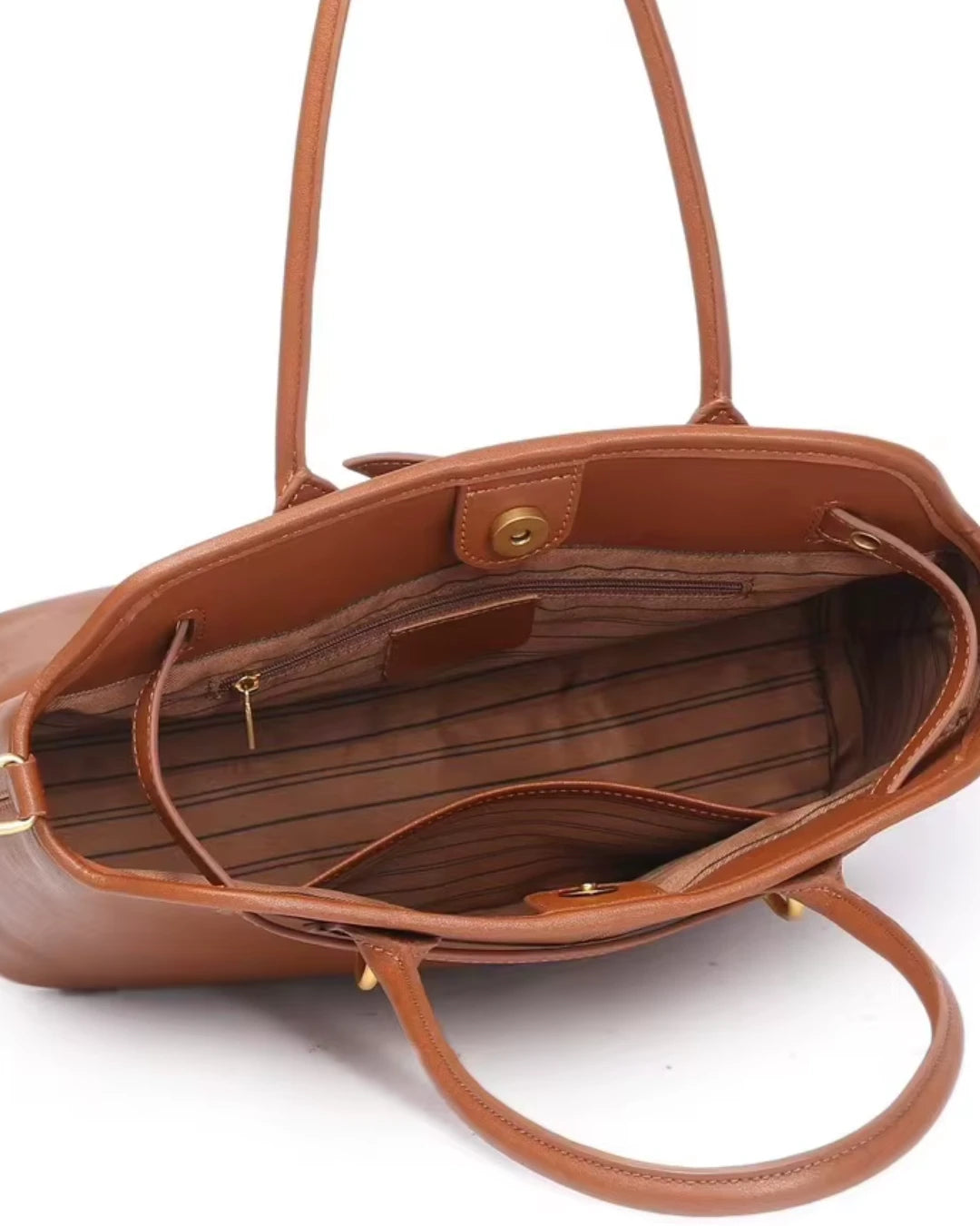 Interior aberto da bolsa feminina Aveline em couro caramelo, mostrando o forro listrado, o compartimento principal e os bolsos internos, incluindo um com zíper.