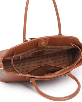 Interior aberto da bolsa feminina Aveline em couro caramelo, mostrando o forro listrado, o compartimento principal e os bolsos internos, incluindo um com zíper.