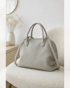 Bolsa feminina de couro cinza claro Vivienne em ambiente claro, com design elegante e alça transversal.
