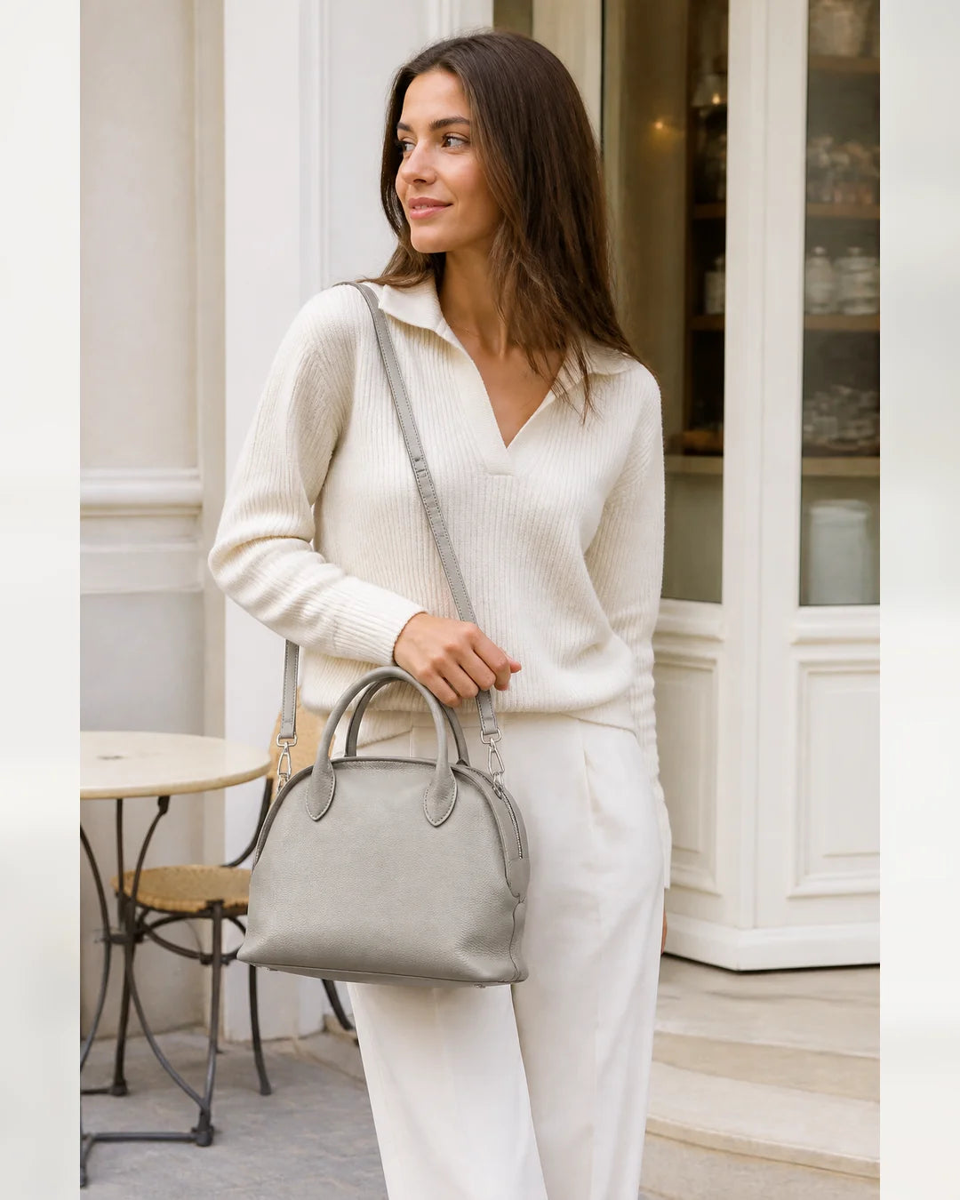 Mulher usando a bolsa feminina de couro cinza claro Vivienne em look claro, destacando proporção e uso no dia a dia.