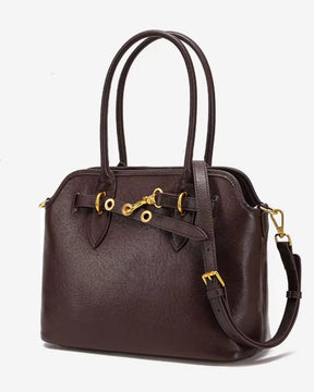 Bolsa feminina Aveline em couro marrom, vista angular, mostrando a estrutura ampla, as alças duplas, a alça transversal regulável e as ferragens douradas.