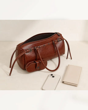 Bolsa feminina de couro marrom Celinne em perspectiva superior, com zíper aberto e itens ao lado, destacando o espaço interno, as alças longas e o porta-óculos acoplado.
