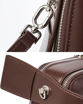 Detalhes da bolsa feminina de couro marrom Elyra, mostrando ferragens prateadas da alça removível, zíper e acabamento lateral em couro.