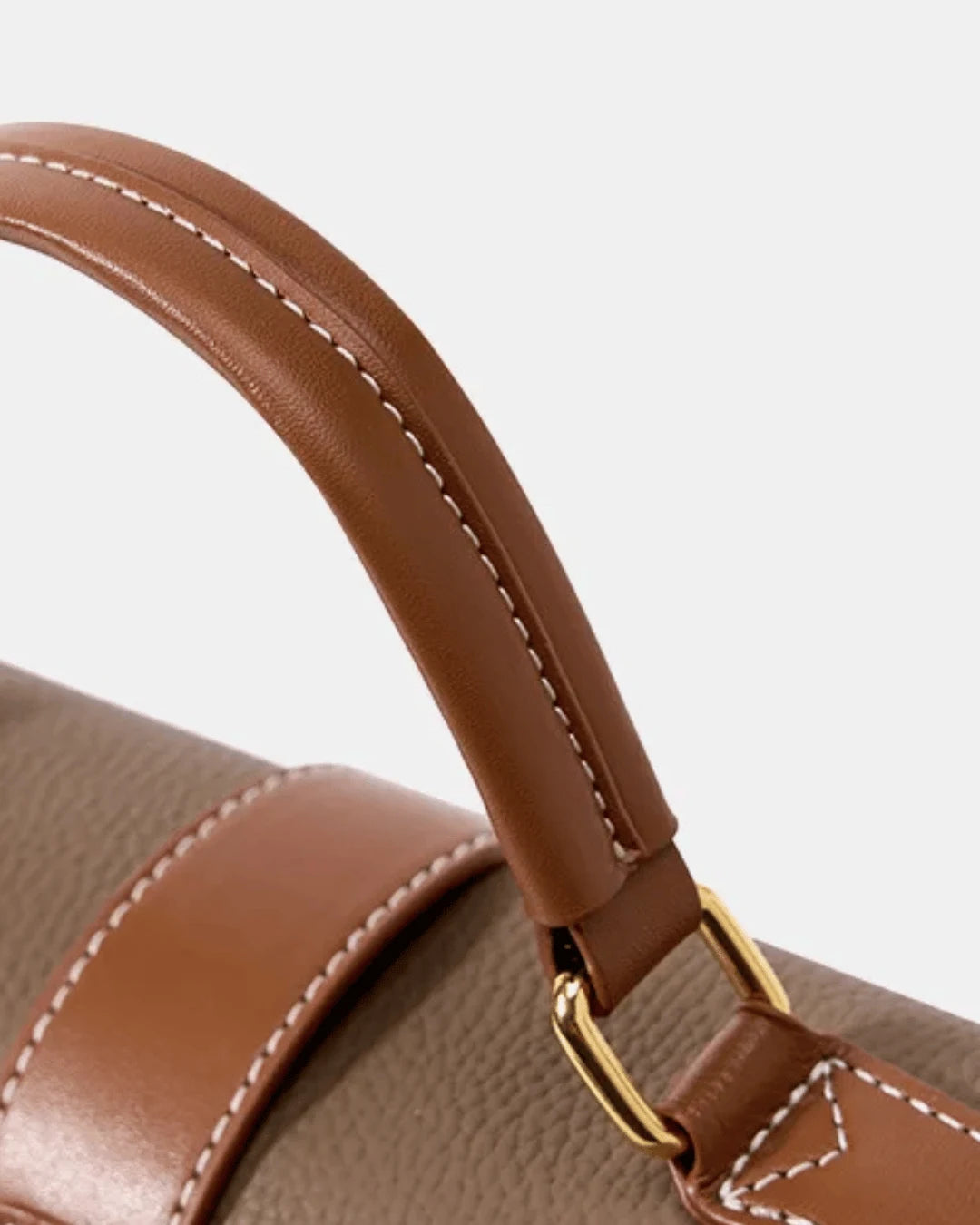 Detalhe da alça de mão caramelo da bolsa feminina Maelle em couro marrom, com costura clara e encaixe metálico dourado.