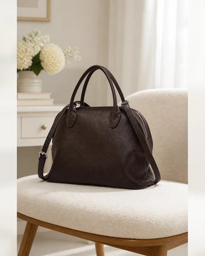 Bolsa feminina de couro marrom Vivienne em ambiente claro, com alças de mão e alça transversal ajustável.