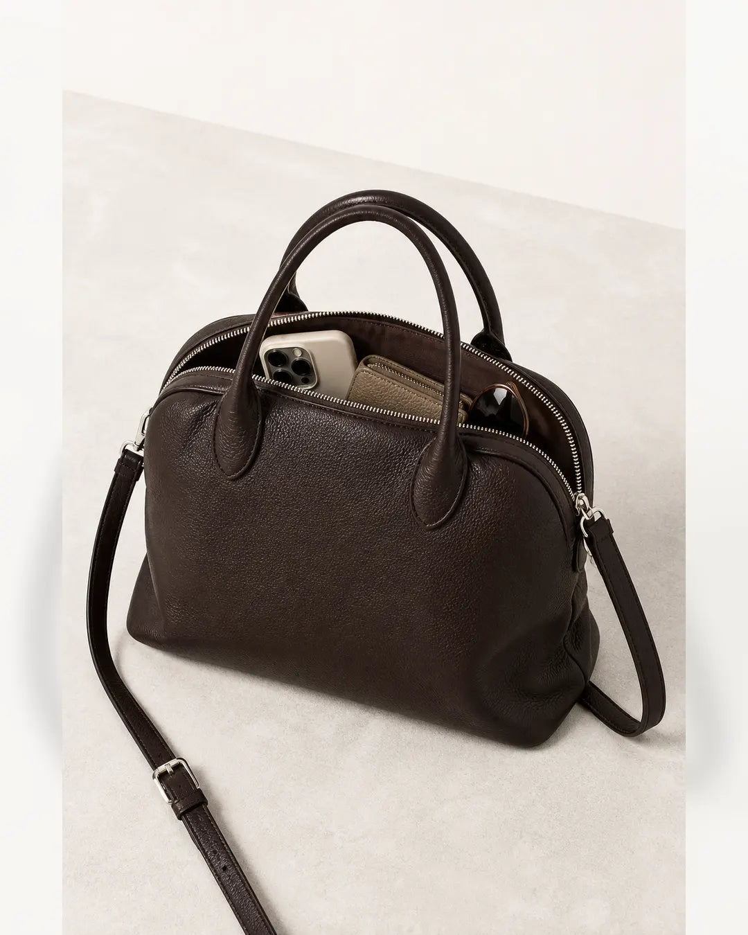 Bolsa feminina de couro marrom Vivienne aberta, mostrando espaço interno para celular, carteira e óculos.