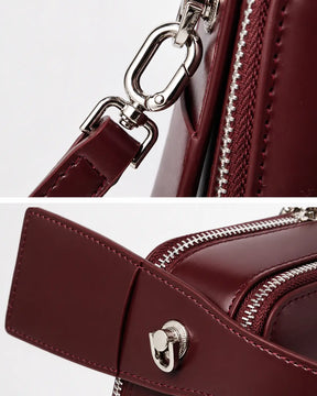 Detalhes da bolsa feminina de couro marsala Elyra, mostrando ferragens prateadas da alça removível, zíper e acabamento lateral em couro.