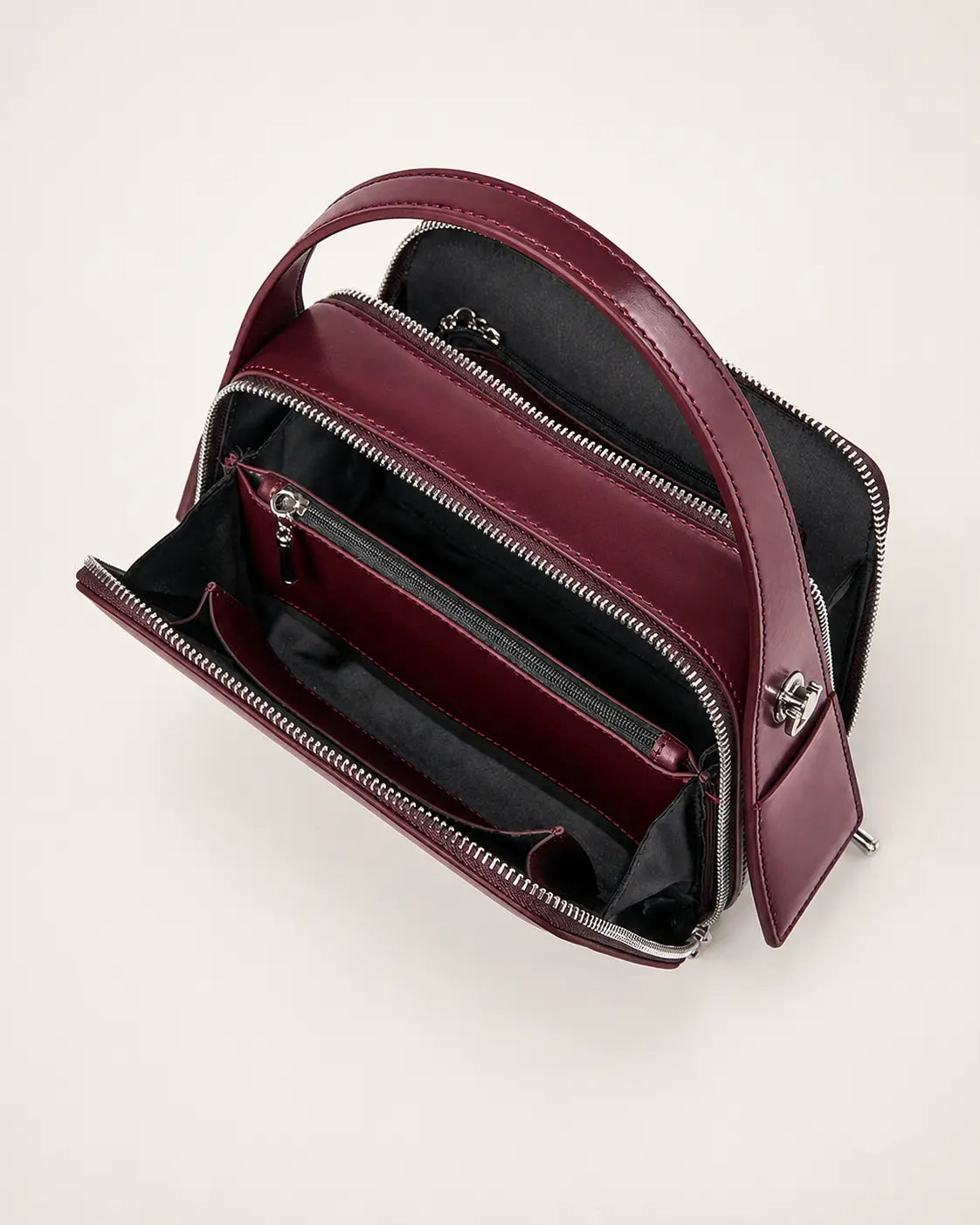 Bolsa feminina de couro marsala Elyra aberta, mostrando os compartimentos com zíper, as divisórias e os bolsos internos para organização.