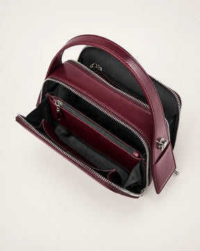 Bolsa feminina de couro marsala Elyra aberta, mostrando os compartimentos com zíper, as divisórias e os bolsos internos para organização.