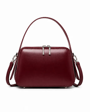 Bolsa feminina de couro marsala Elyra, vista frontal, com alça de mão, alça transversal removível, ferragens prateadas e fechamento superior em zíper.