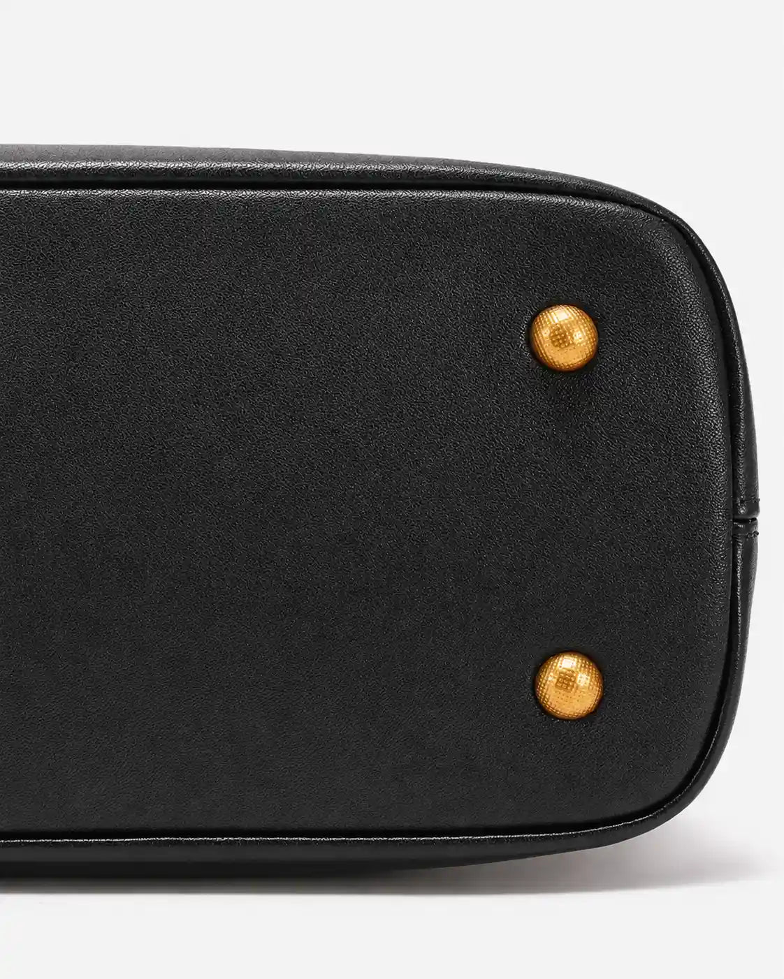 Detalhe da base da bolsa feminina Aveline em couro preto, mostrando o acabamento estruturado, o contorno reforçado e os pés metálicos dourados.