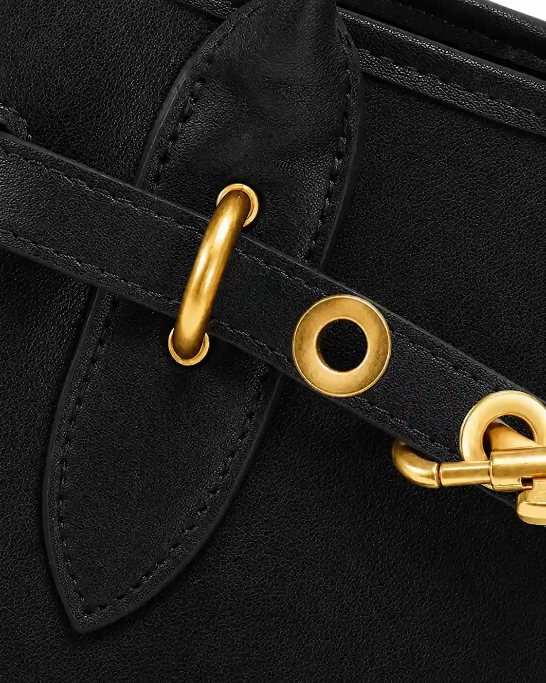Detalhe frontal da bolsa feminina Aveline em couro preto, com tira decorativa, ilhoses, argolas, mosquetão dourado e costuras aparentes.