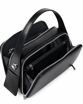 Bolsa feminina de couro preta Elyra aberta, mostrando os compartimentos com zíper, as divisórias e os bolsos internos para organização.
