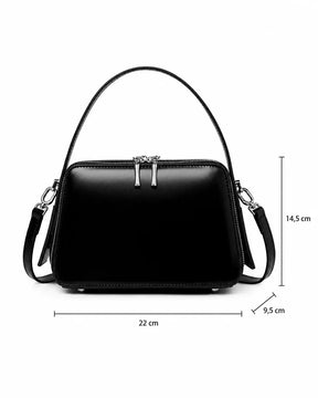 Bolsa feminina de couro preta Elyra, vista frontal, com alça de mão, alça transversal removível e indicação das medidas de 22 cm de largura, 14,5 cm de altura e 9,5 cm de profundidade.