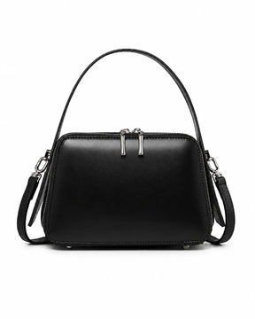 Bolsa feminina de couro preta Elyra, vista frontal, com alça de mão, alça transversal removível, ferragens prateadas e fechamento superior em zíper.