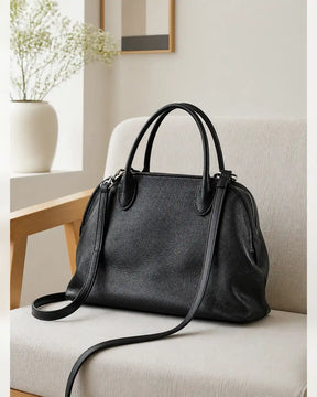 Bolsa feminina de couro preta Vivienne em ambiente claro, com design estruturado e alça transversal.