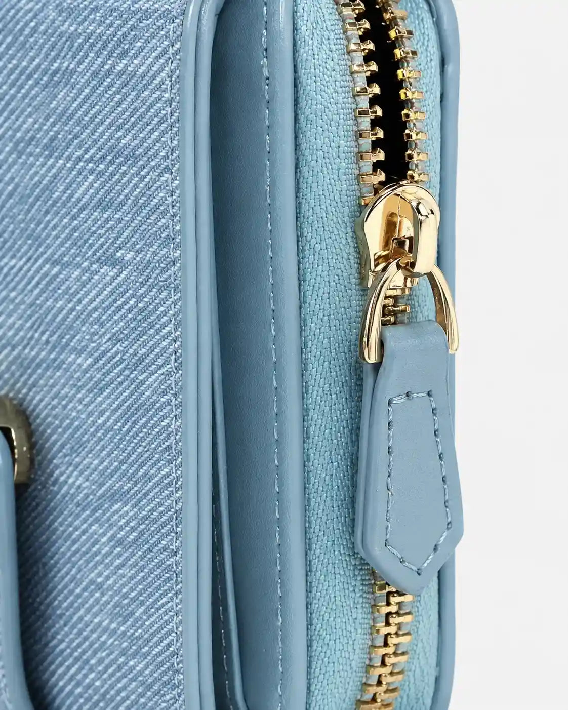 Detalhe do zíper metálico dourado e do puxador azul da carteira feminina Lysene, com costuras aparentes e acabamento texturizado.
