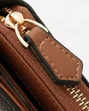 Detalhe do puxador e dos dentes metálicos do zíper da carteira feminina Valenne, com acabamento caramelo, bordas escuras e costuras claras.
