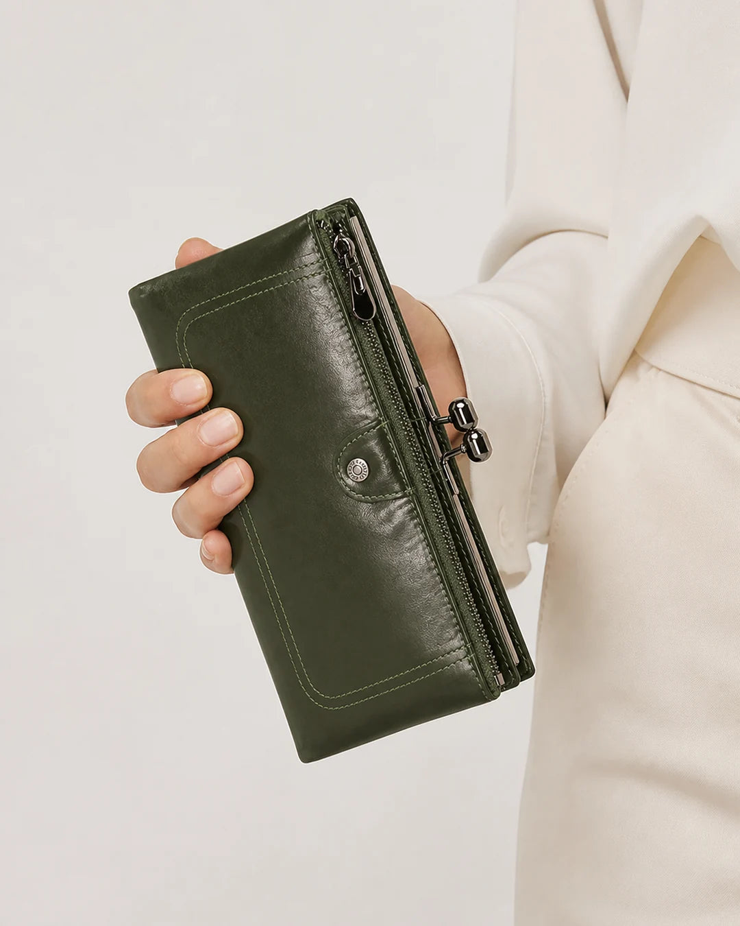 Carteira feminina de couro green Delphine sendo segurada na mão, com acabamento liso, bolso externo com zíper e fecho metálico lateral.