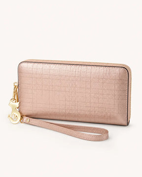 Carteira feminina de couro rose Aurielle em vista fechada, com design alongado, textura discreta, fechamento em zíper e alça de pulso com detalhe metálico dourado.
