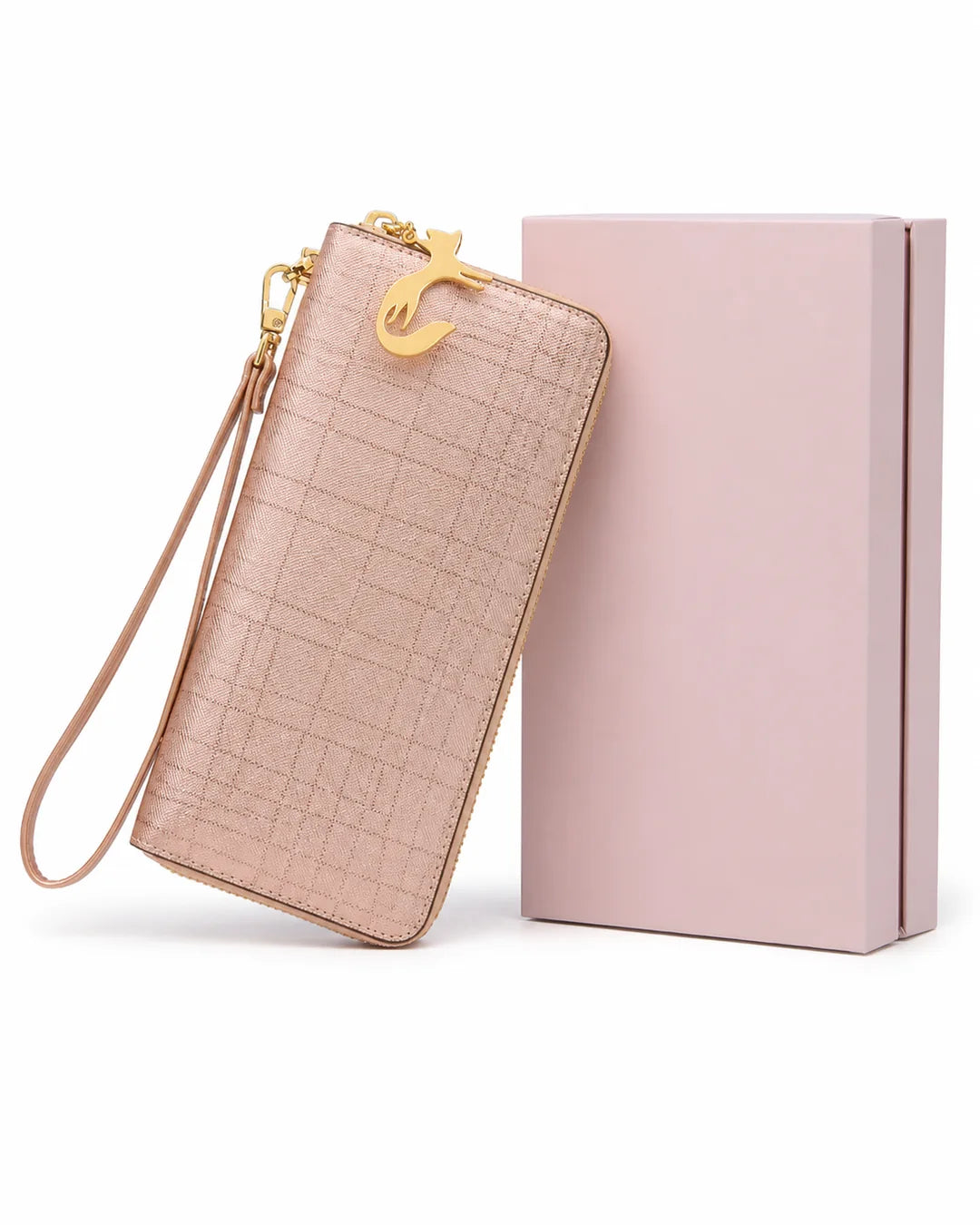 Carteira feminina de couro rose Aurielle posicionada ao lado de uma caixa rosa, com formato alongado, alça de mão e pingente dourado em formato de gato.
