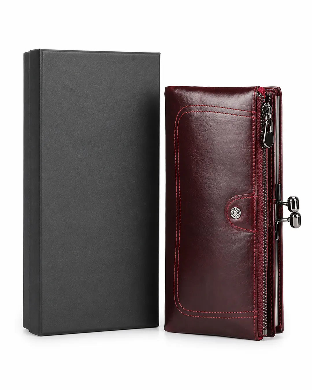 Carteira feminina de couro vermelha Delphine posicionada ao lado de uma caixa preta, com design alongado, bolso externo com zíper e fecho metálico lateral.
