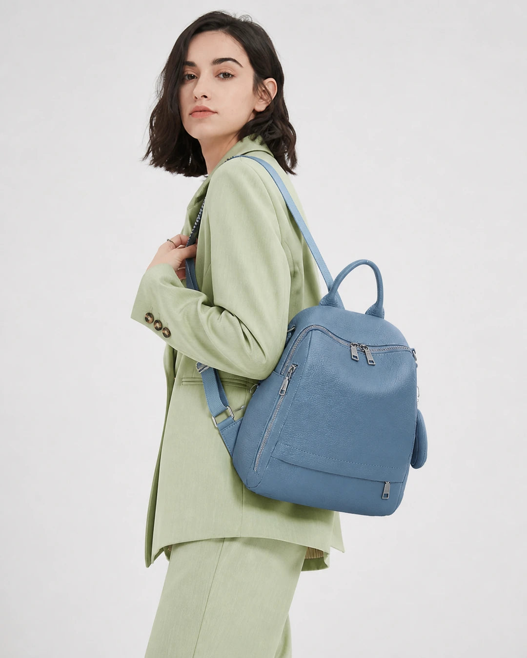 Mulher usando a mochila feminina de couro azul Serelle nas costas, mostrando o caimento, o tamanho e o visual moderno da peça.
