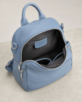 Mochila feminina de couro azul Serelle aberta, exibindo o interior espaçoso com forro escuro, divisórias internas e bolso com zíper.
