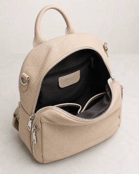 Mochila feminina de couro bege Serelle aberta, mostrando o interior espaçoso com forro escuro, divisórias internas e bolso com zíper.
