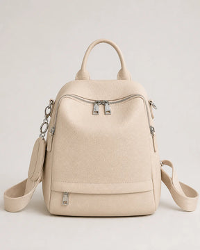 Mochila feminina de couro bege Serelle em vista frontal, com alça de mão, bolsos externos com zíper e design moderno.
