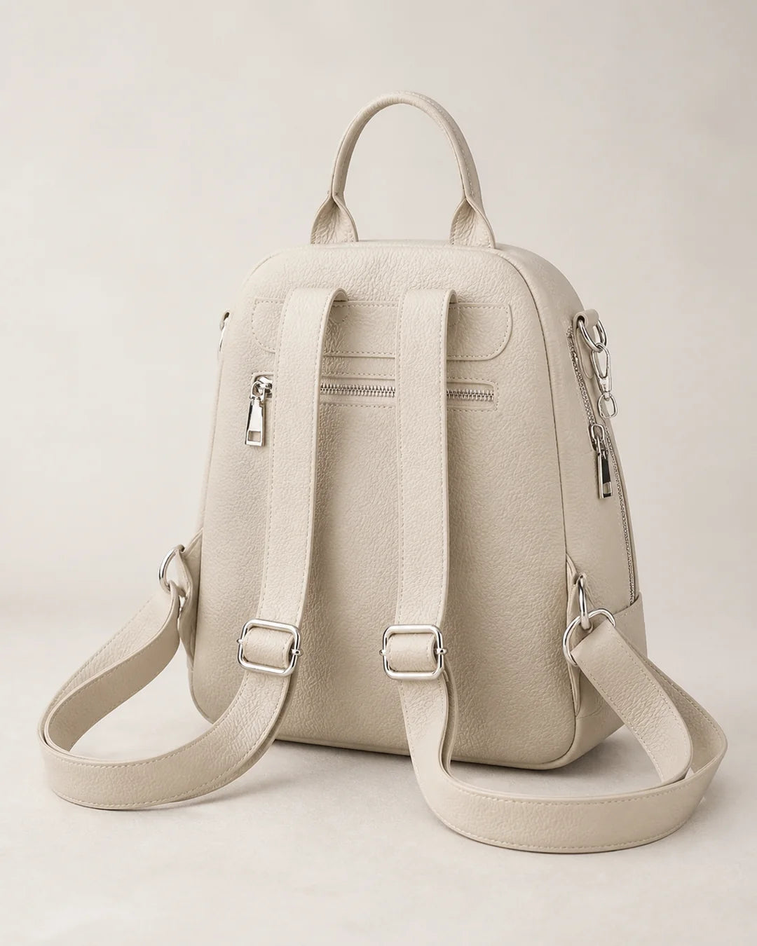 Mochila feminina de couro bege Serelle em vista traseira, com alças ajustáveis, bolso traseiro com zíper e acabamento em couro texturizado.
