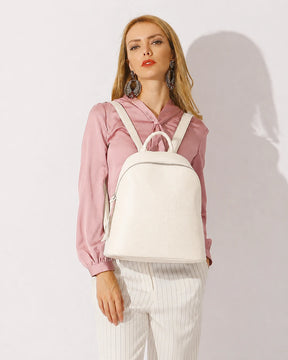 Mulher usando a mochila feminina de couro branca Aveline nas costas, destacando o tamanho, o caimento e o estilo elegante da peça.
