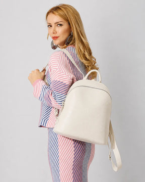 Mulher usando a mochila feminina de couro branca Aveline em vista lateral, evidenciando o formato estruturado, o acabamento liso e as alças ajustáveis.