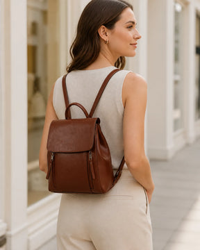 Mulher usando a mochila feminina de couro café Corinne nas costas, mostrando o caimento e o visual sofisticado da peça.