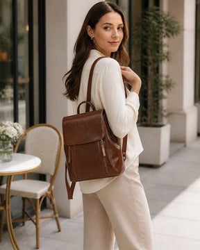Mulher usando a mochila feminina de couro café Corinne em ambiente externo, destacando estilo casual elegante e versatilidade.