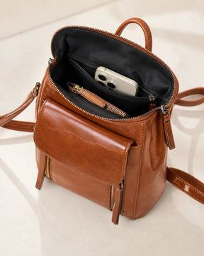 Mochila feminina de couro marrom Corinne aberta, mostrando compartimentos internos para celular, carteira e itens pessoais.