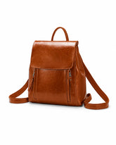 Mochila feminina de couro marrom Corinne em vista frontal sobre fundo claro, com aba superior e bolsos frontais com zíper.