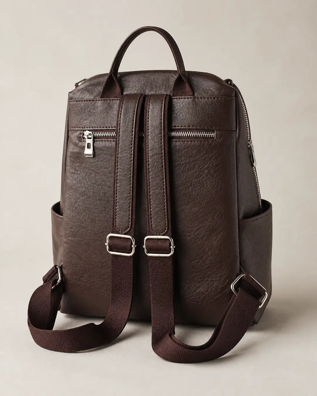 Mochila feminina de couro marrom Lorien em vista traseira, com alças ajustáveis, bolso traseiro com zíper e estrutura prática para o dia a dia.
