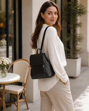 Mulher usando a mochila feminina de couro preta Corinne em ambiente externo, mostrando o visual sofisticado e versátil da peça.