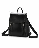 Mochila feminina de couro preta Corinne em vista frontal sobre fundo claro, com aba superior e bolsos frontais com zíper.