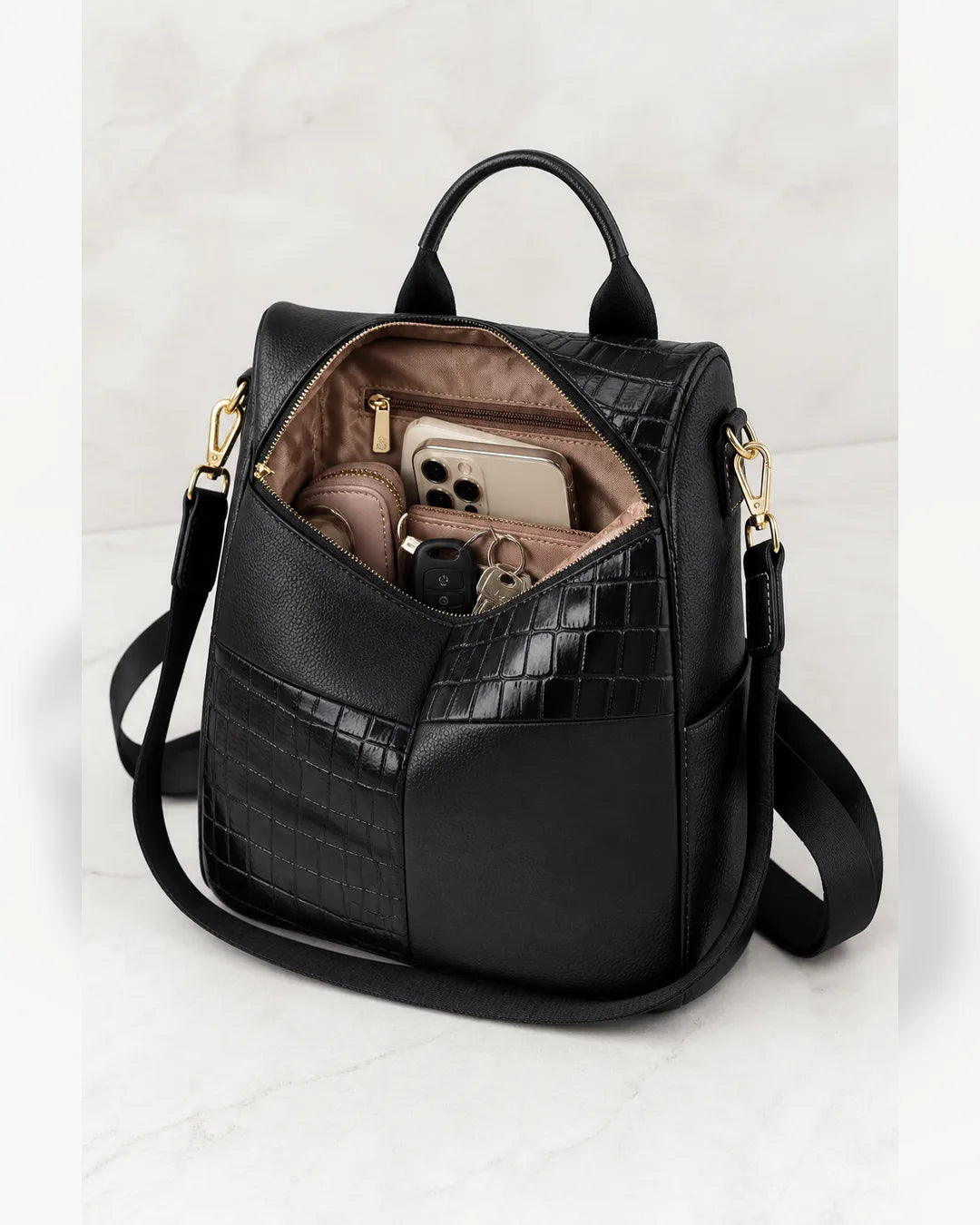 Mochila feminina de couro preta Elvienne aberta, mostrando compartimentos internos para celular, carteira, chaves e acessórios.