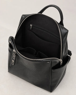 Mochila feminina de couro preta Lorien aberta, exibindo o interior espaçoso com divisórias internas e bolso com zíper para melhor organização.

