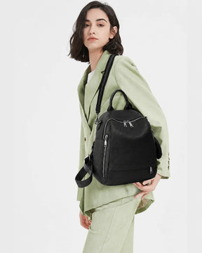 Mulher usando a mochila feminina de couro preta Serelle no ombro, mostrando o tamanho, o caimento e o visual elegante da peça.

