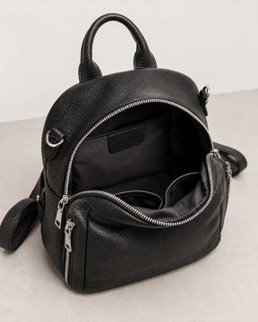Mochila feminina de couro preta Serelle aberta, exibindo o interior espaçoso com forro escuro e divisórias internas para melhor organização.
