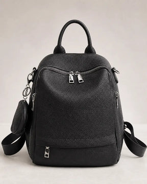 Mochila feminina de couro preta Serelle em vista frontal sobre fundo neutro, destacando o acabamento texturizado e os compartimentos com zíper.
