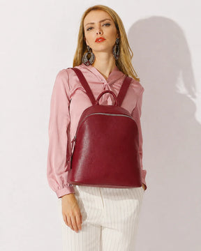 Mulher usando a mochila feminina de couro vermelha Aveline nas costas, destacando o tamanho, o caimento e o visual elegante da peça.
