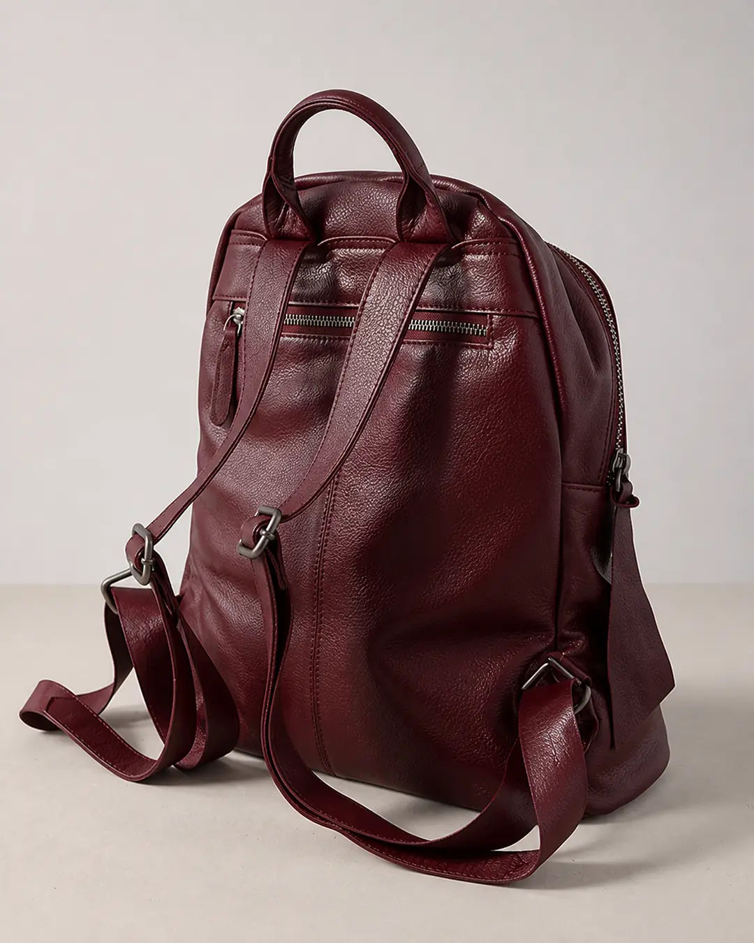 Mochila feminina de couro vermelha Aveline em vista traseira, com alça de mão, alças ajustáveis, bolso externo com zíper e acabamento macio.
