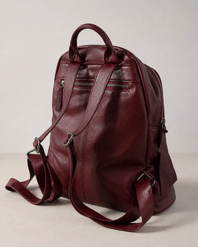 Mochila feminina de couro vermelha Aveline em vista traseira, com alça de mão, alças ajustáveis, bolso externo com zíper e acabamento macio.
